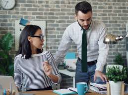 a man and a woman standing in front of a laptop