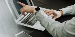 two people sitting at a table with laptops